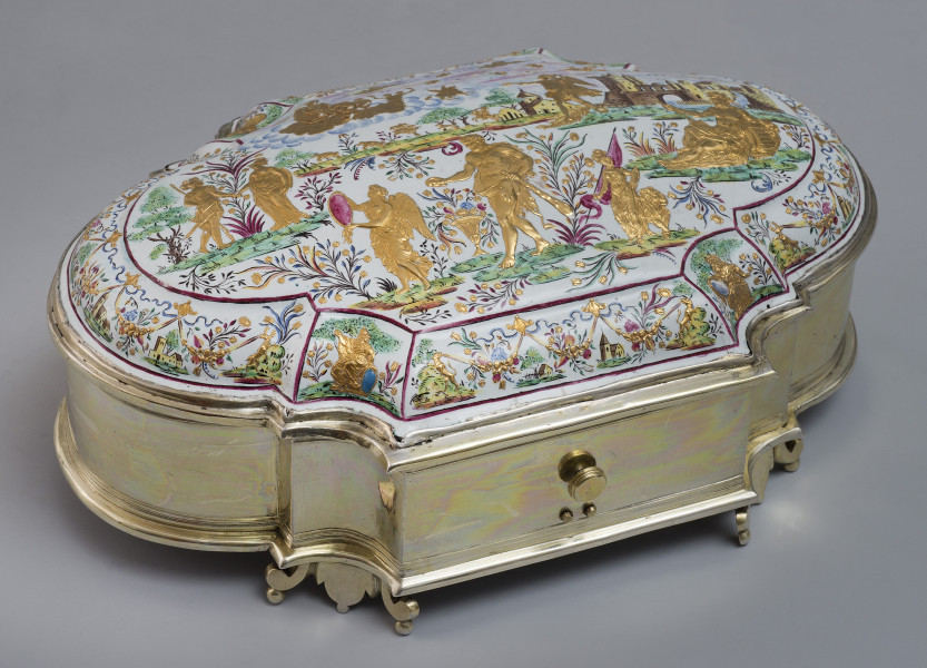 ujęcie 3/4. Ujęcie z góry, wieczko wypukłe bogato zdobione, na białym tle podzielone czerwoną cienką ramką na mniejsze sceny na skośnych elementach i scenę główną w centralnej części. Boczne sceny kobiece postacie w zbroi z tarczami, zabudowania, psy elementy, roślinne owoce i kwiaty, w środku pejzaż sześć złotych postaci z kolorowymi roślinami, koszem kwiatów oraz w tle zabudowania z zamkiem. Bok puzderka złoty o zaokrąglonych węższych bokach, szersze boki z czterema półokrągłymi wcięciami.