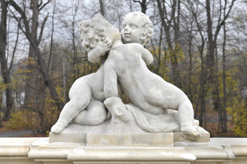 ujęcie od strony pierwszej. Nadzy i pulchni chłopiec z dziewczyną, siedzą na rozpostartej ma pniu draperii. Obejmując się kierują usta do pocałunku. Chłopiec jest widoczny od tyłu. Jego włosy są krótki i kręcone.