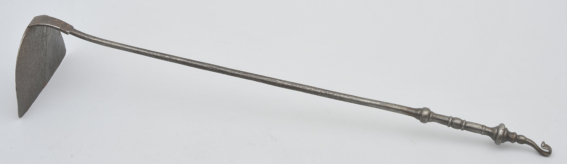 ujęcie 3/4. Widok z boku i lekko z góry, rączka skierowana jest w lewo i w dół. Wygarniacz opiera się na krawędzi sztychu, który jest półkolisty w zarysie i zagięty pod kątem 90 stopni. Toczona rączka zakończona jest haczykiem do wieszania.