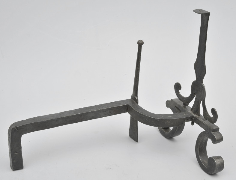 Ujęcie 3/4. Widok z boku, lekko z tyłu i od góry, z przodem po prawej stronie. W większości pręt prosty, bliżej przodu wygięty w prawo. W miejscu wygięcia smukły szpikulec. Pręt łączy się z przednią częścią obiektu przy metalowej płytce. Powyżej niej pionowy trzpień. Poniżej zwężenia na trzpieniu odchodzą dwa wygięte ramiona. Od płytki odchodzą wygięte stopki. Obiekt w całości czarny, lekko błyszczący.