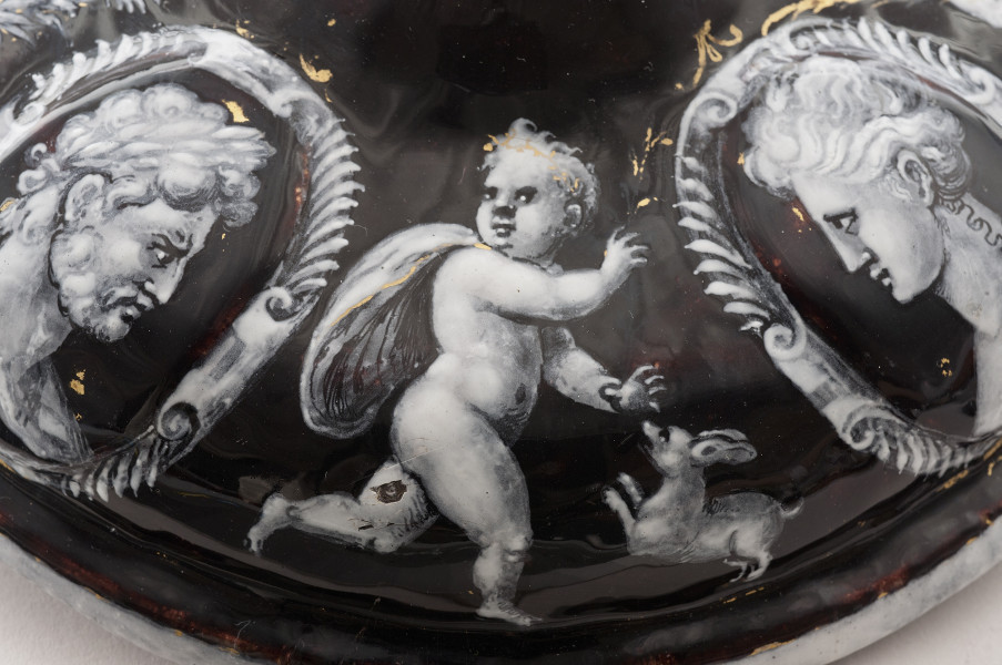 fragment zewnętrznej części pokrywy, po bokach dekoracja medalionów z głowami antycznymi, po środku amorek z małym zwierzęciem.