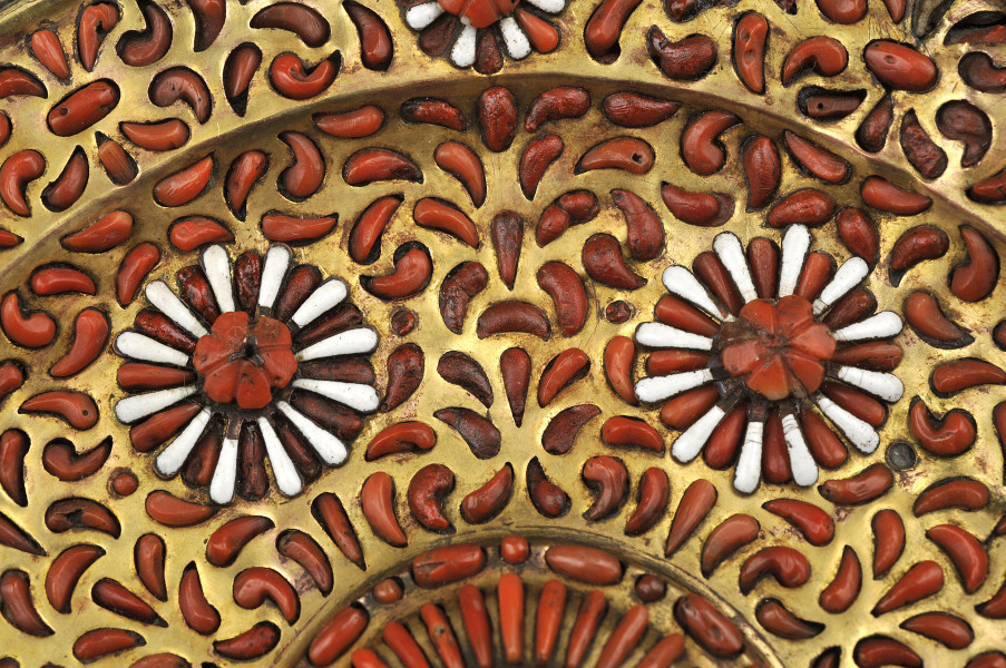 ujęcie z góry – fragment. Zbieżnie na fragment patery, dwa kwiaty z biało czerwonymi płatkami, kompozycję uzupełniają liczne czerwone koralowe płatki na złotym tle.