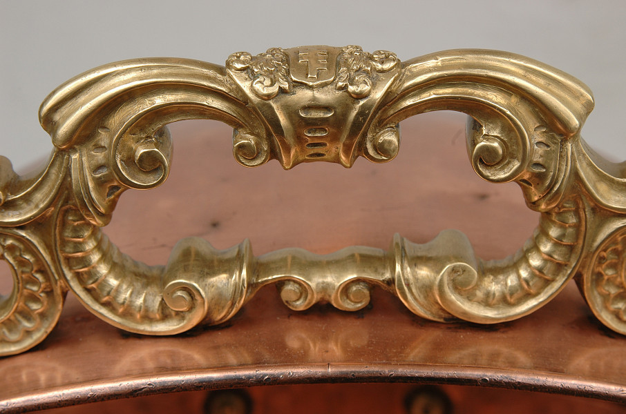 Mosiężne, cyzelowane ucho z motywem ornamentu chrząstkowo-małżowinowego na górnej ściance. Ucho w kolorze złotym. Ścianka pojemnika w kolorze jasnobrązowym.