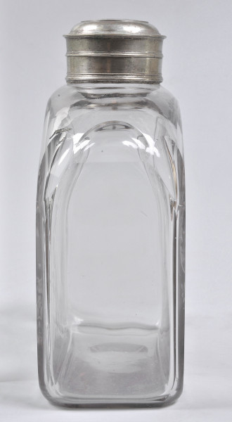 Strona druga, ścianka wąska, wysoka i płaska, bezbarwna. Na szczycie łagodnie się zwęża do srebrnego obramienia szyjki. Na butlę nałożona jest nakrętka. 