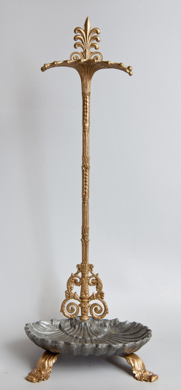 Ujęcie z przodu. Na dole widoczna podstawka w kształcie muszli. Pod podstawką widoczne są dwie wygięte stopki w motywie roślinnym. Przez tył podstawy przechodzi trzpień pokryty płaskorzeźbami. W dolnej partii, zwoje z wici akantowej. U góry trzpień przechodzi w płaską sterczynę. Poniżej sterczyny podpórka na przybory.