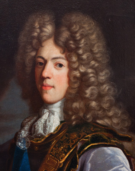 fragment lica obrazu. Ujęcie trzy czwarte w prawo na tle pochmurnego nieba. Królewicz w czarnym kirysie ze złotymi zdobieniami. Pierś ma przepasaną wstęgą, na szyi żabot. Ma pociągłą twarz, pełne usta i wysoką perukę z kaskady siwych loków. Ciemne oczy kieruje na widza.