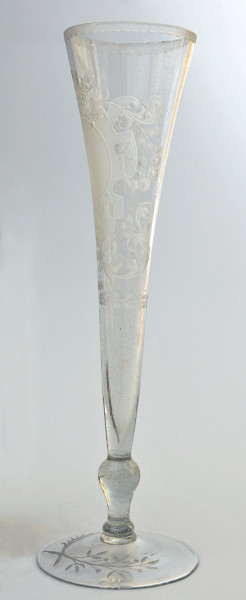 strona druga. Ukazany bokiem smukły kielich, lejkowato rozszerzający się ku górze. Na okrągłej stopie umieszczone dwie skrzyżowane gałązki - lauru i palmy. Wyżej tralkowata nóżka, łącząca stopę z czaszą. Bogata dekoracja z ukoronowanym polem herbowym jest widoczna w połowie.