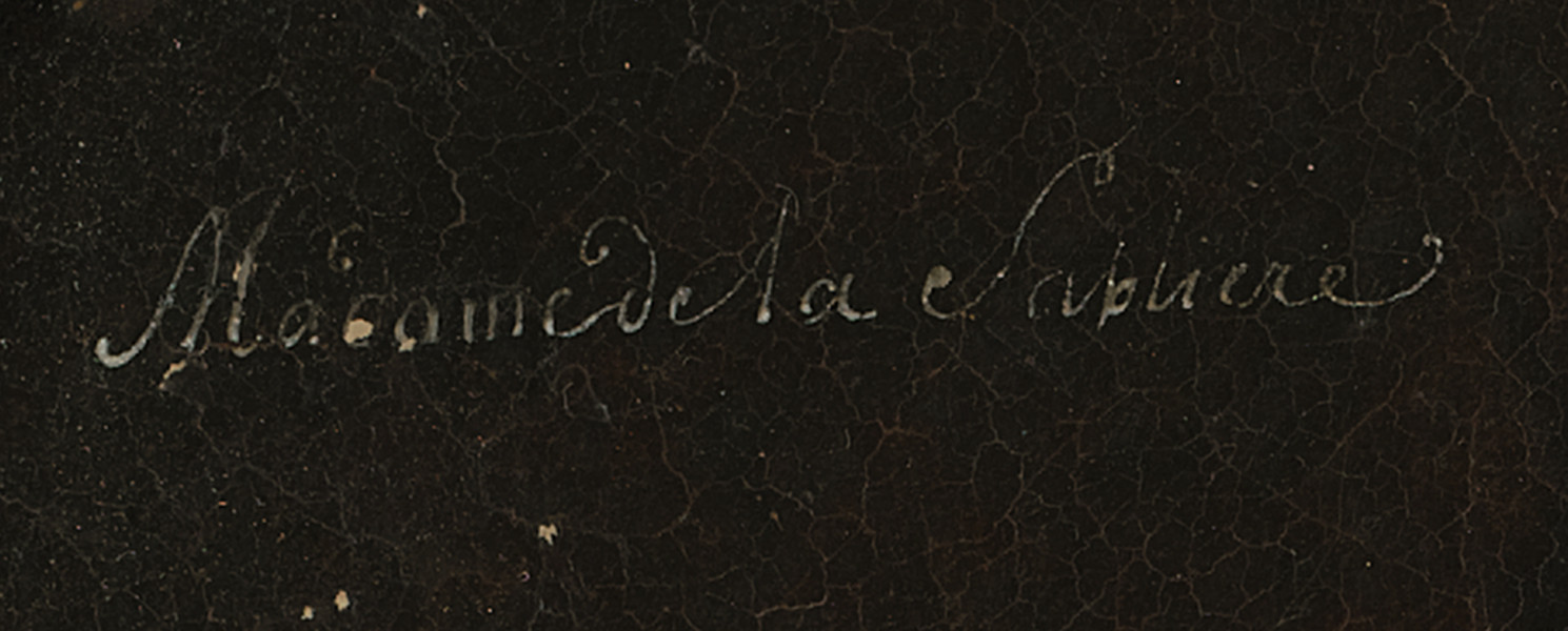 Fragment lica obrazu - napis białą farbą kursywą: Madame de la Sablliere. Tło ciemnobrązowe.