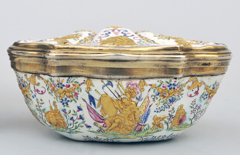 ujęcie z przodu. Widok z boku. Pokrywka w kształcie muszli, dolna część na białym tle w centralnej części siedząca na tle sztandarów postać z tarczą wspartą na kolanach otoczona bogato zdobioną dekoracją roślinną, po lewej stronie mniejsza postać z tarczą po prawej mały gryf i postać kobieca.