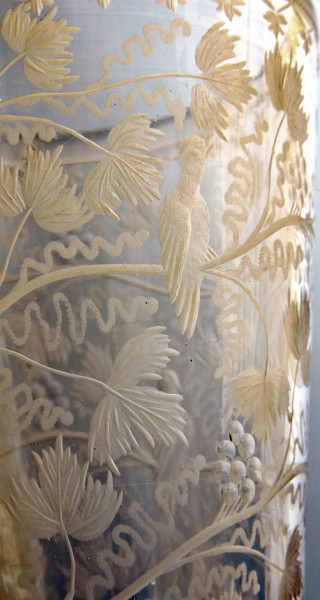 zbliżenie na rytowaną dekorację. Na gałązkach winnej latorośli, między liśćmi i owocami siedzi ptak. Bogata dekoracja zajmuje cały ukazany fragment czaszy.