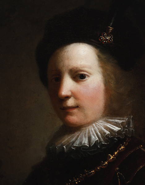 Fragment lica obrazu. Zbliżenie na twarz chłopca. Głowa 3/4 w lewo. Okrągła, dziecinna twarz oświetlona jest w mroku punktowo. Na szyi modela biała kryza, na piersi złoty łańcuch, na głowie ciemny beret, ozdobiony egretą.