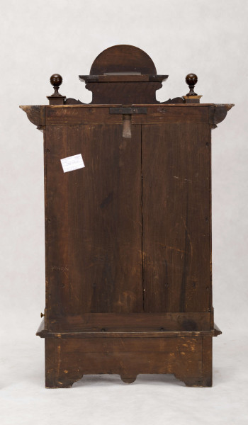 Pozytywka w szafce eklektycznej, drewnianej pokrytej okleiną z drewna orzechowego. Szafka prostokątna, pionowa, z ozdobnym zwieńczeniem, na niskich nóżkach, na froncie drzwiczki. Pośrodku zwieńczenia prostokątny cokolik z muszlą, po bokach kuliste sterczynki na sześciennych podstawach. Gzyms wieńczący górą wysunięty z rytowanym pośrodku  napisem 