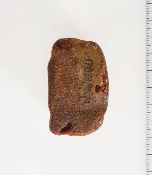 Półwytwór bursztynu kształtem zbliżony do sześcianu. Wyraźnie widoczne ślady szlifów i nawierceń.