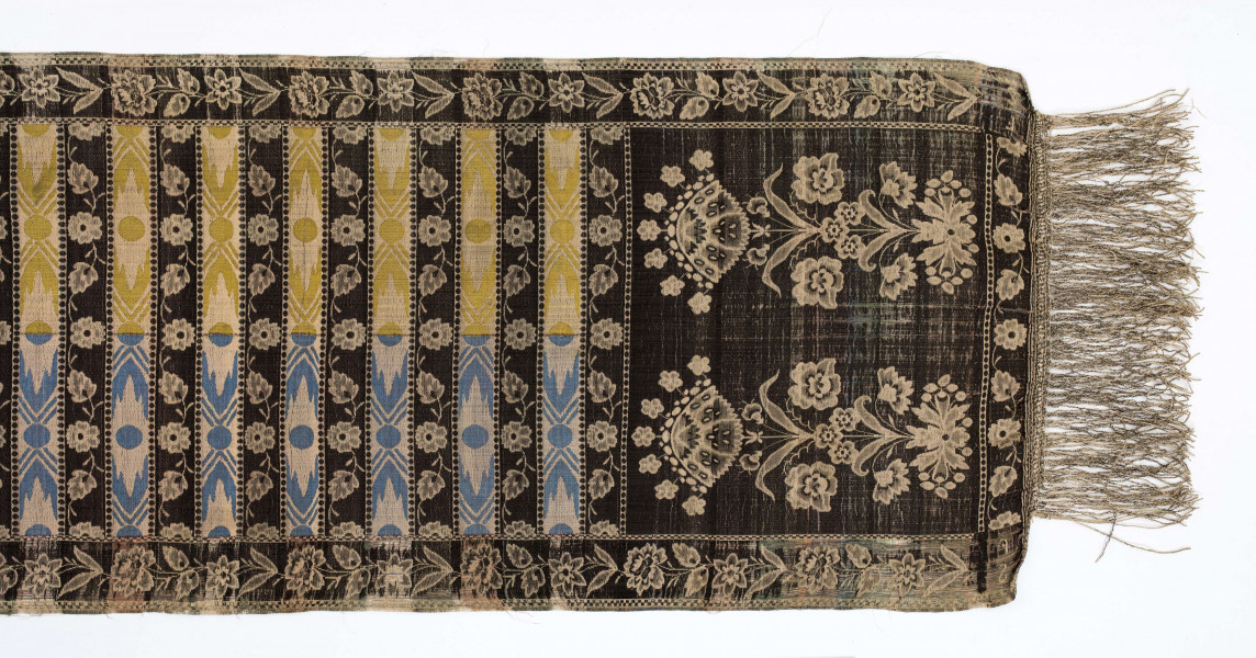 Pas kontuszowy czterostronny
Ornament: 
głowy - dwa motywy krzaczków kwiatowych wyrastających z liściastej rozety
środek - poprzeczne pólka na przemian z motywami wici kwiatowej i wydłużonych rombów z szelążkami
obrzeżenia - pionowe z motywami gałązek z kawiatami i liśćmi; poziome - motywy wici kwiatowej jak w pólkach
obwódki - w szachownicę, romby i groszki
Koloryt:
pr. - tło słomkowe, ornament różowy, biały, zielony, błękitny, jaznobrązowy
l. - tło czarne, jedynie w pólkach z rombamiw połowie błękitne, w połowie oliwkowozłote, ornament słomkowy
W narożnikach głów wytkana sygnatura: F/S (leżące)
Frędzla doszyta jedwabna, pleciona z nici kremowych z dodatkiem czarnych
