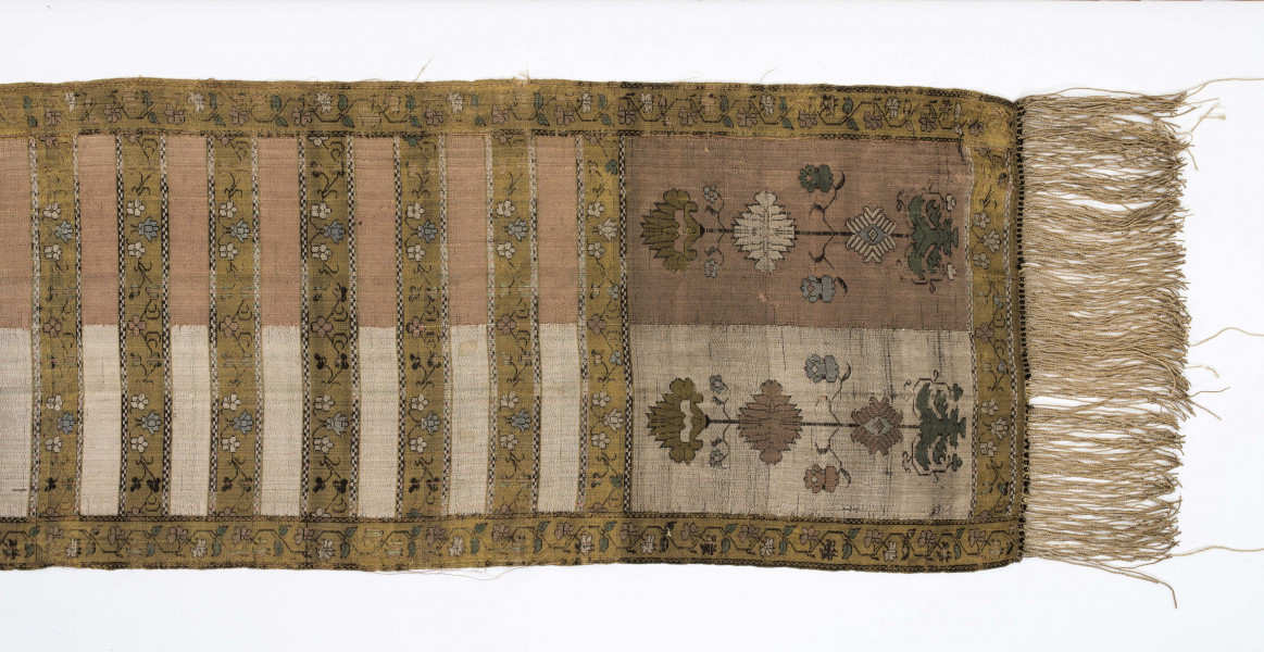 Pas kontuszowy czterostronny.
Ornament:
głowy- dwa motywy ukwiecinych łodyg umieszczonych w wazonach przypominajacych palmety- stylizowane , silna geometryzacja motywów. 
wciąż pasa- poprzeczne pólka z motywem wici kwiatowej i rzuty rozetek, na przemian
obrzeżenia- pionowe z motywem zgeometryzowanej wici kwiatowej poziome- jak w  pólkach 
kolor:pr. -  tło głów i pólek z wicią i obrzeżeń  żółte gładkie pólka w połowie różowe  w połowie różowe, wić brązowa kwiaty niebieskie, łososiowe i żółte
l. tło brązowe wzór słomkowy
Frendzla doszyta słomkowa.
