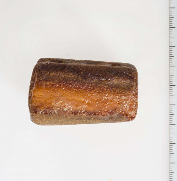 Półwytwór bursztynu kształtem zbliżony do sześcianu. Wyraźnie widoczne ślady szlifów i nawierceń.