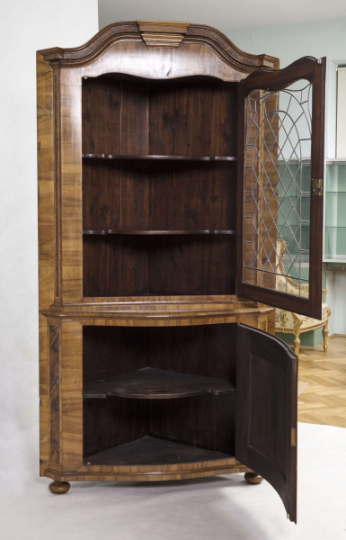 Szafa dwukondygnacyjna, z falistym zwieńczeniem, na nóżkach w kształcie spłaszczonych kul, wnętrze na planie trójkąta z półkami o falistych frontach. W części dolnej drzwi o wypukłym profilu zdobione fornirowanym wzorem: w centrum romb z przedstawieniem ptaka na gałęzi, wokół wzór szachownicy, krawędzie ujęte w ramę. W części górnej drzwi o falistym zwieńczeniu  oszklone szybkami łączonymi ołowiem.  
Oryginalny jest tylko front - pochodzący być może z szafy ściennej - całe wnętrze wykonano w XX wieku.  
