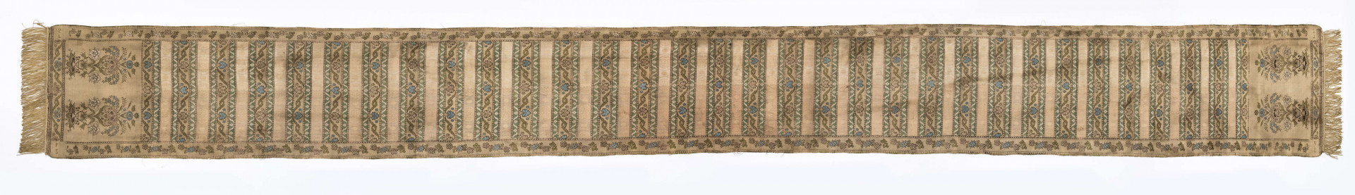 Pas 4-stronny. 
Ornament: głowy - krzaczki kwiatowe w wazonach; środek - poprzeczne pólka w układzie a,b,a,c (a - motyw wijacego sie wężyka, b - medaliony z rozetami, c - wić kwiatowa), obrzeża pionowe z gałązkami kwiatowymi, poziome - jak pólka c.
Koloryt: prawa strona - tło słomkowe, nieznacznie zróżnicowane w każdej połowie, zielen, błękit, żółty; lewa strona - tło brązowe głów i obrzeżeń, ornament - tło słomkowe, wzór j.w..
Fredzla doszyta jedwabna, pleciona, słomkowożółta