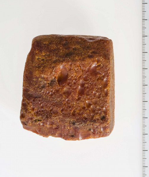 Surowiec wstępnie obrobiony. Kształt prostokątny, kolor pomarańczywy. Widoczne ślady obróbki.