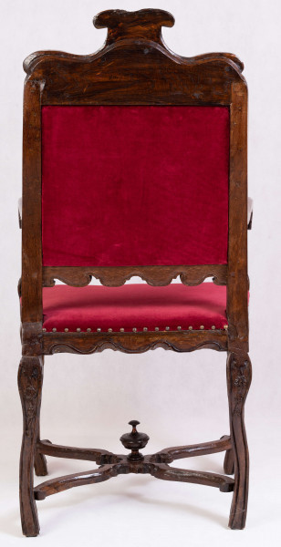 S/Mb/132/ML - Fotel z tapicerowanym siedziskiem i oparciem, na czterech nogach wygiętych kabriolowo, połączonych skrzyżowanymi trawersami. Oskrzynienie prostokątne z fartuchem wysiętym w zęby przypominające lambrekin. Oparcie ażurowe, prostokątne, od góry zamknięte faliście z wolutowym szczytem pośrodku, deska dolna wycięta analogicznie do fartucha oskrzyni. Poręcze drewniane wyrastają z ramiaków bocznych oparcia, lekko wygięte, zakończone wolutami. Podpórki poręczy profilowane i rzeźbione w dolnej części.podobnie opracowanwe nogi, rzeźbione w liscie akantu u nasady, połączone wolutowymi trawersami z okrągłą sterczynką na skrzyżowaniu. Tapicerka na pasach, pokrycie bordowym aksamitem, na brzegach mosiężne gwoździe






  