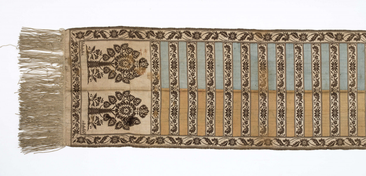 Pas kontuszowy czterostronny
Ornament
Głowy- motyw dwóch drzewek, których koronę stanowi owalna rozeta otoczona listkami, rozeta i listki wypełnione małymi kwiatkami. Drzewko wyrasta z lekko pofalowanego gruntu po bokach dwa małe krzaczki kwiatowe. 
Wciąż- pasa w poprzeczne pólka na przemian gładkie i z motywem wici kwiatowej.
Obrzeżenia- pionowe z motywem wici złożonej z kwiatów i listków palmowych, poziome jak w  pólkach.
Kolory: karmazynowy, błękitny, zielony, kremowy i brązowy
Pas sygnowany- w głowach tkany napis: S Filsjean Wkobyłce
Krótsze boki z doszytą długą frendzlą