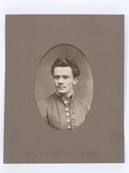 Włosy lekko falujące, zaczesane do góry, wąsik, głowa zwrócona w prawą stronę.