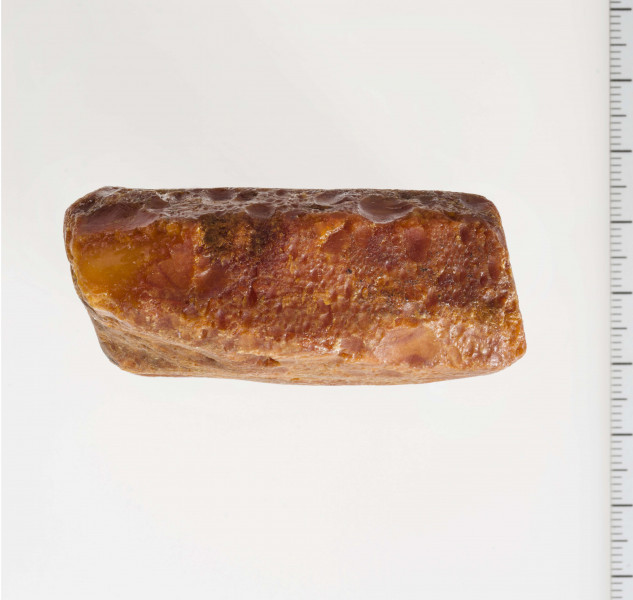 Surowiec wstępnie obrobiony. Kształt prostokątny, kolor pomarańczywy. Widoczne ślady obróbki.