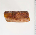 Surowiec wstępnie obrobiony. Kształt prostokątny, kolor pomarańczywy. Widoczne ślady obróbki.