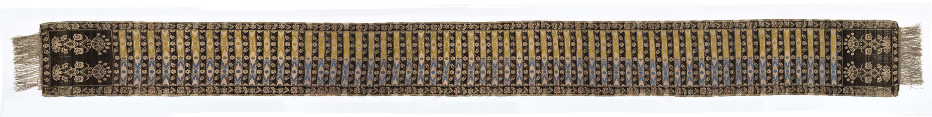 Pas kontuszowy czterostronny
Ornament: 
głowy - dwa motywy krzaczków kwiatowych wyrastających z liściastej rozety
środek - poprzeczne pólka na przemian z motywami wici kwiatowej i wydłużonych rombów z szelążkami
obrzeżenia - pionowe z motywami gałązek z kawiatami i liśćmi; poziome - motywy wici kwiatowej jak w pólkach
obwódki - w szachownicę, romby i groszki
Koloryt:
pr. - tło słomkowe, ornament różowy, biały, zielony, błękitny, jaznobrązowy
l. - tło czarne, jedynie w pólkach z rombamiw połowie błękitne, w połowie oliwkowozłote, ornament słomkowy
W narożnikach głów wytkana sygnatura: F/S (leżące)
Frędzla doszyta jedwabna, pleciona z nici kremowych z dodatkiem czarnych
