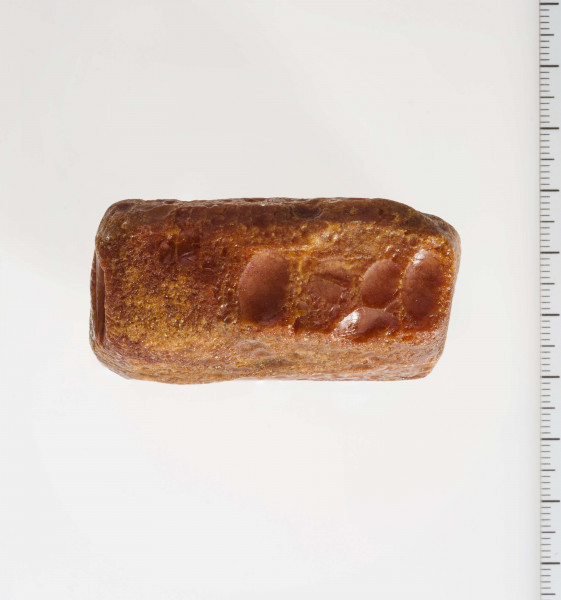 Surowiec wstępnie obrobiony. Kształt prostokątny, kolor pomarańczywy. Widoczne ślady obróbki.