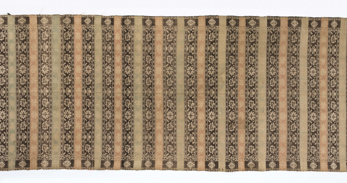 Pas kontuszowy dwustronny.
Ornament: 
głowy-trzy motywy stylizowanego kwiatu  goździka (każdy o czterech zgeometryzowanych płatkach)
wciąż pasa- poprzeczne pólka o kolejnych powtarzajacych się sekwencjach motywów:
-ciąg palmetek
-stylizowane kwiaty na tle łososiowym
-stylizowane kwiaty na tle zielonm
obrzeżenie- nieznacznie wyodrebnione dekorowane rozetką
Frędzla wysnuta z osnowy