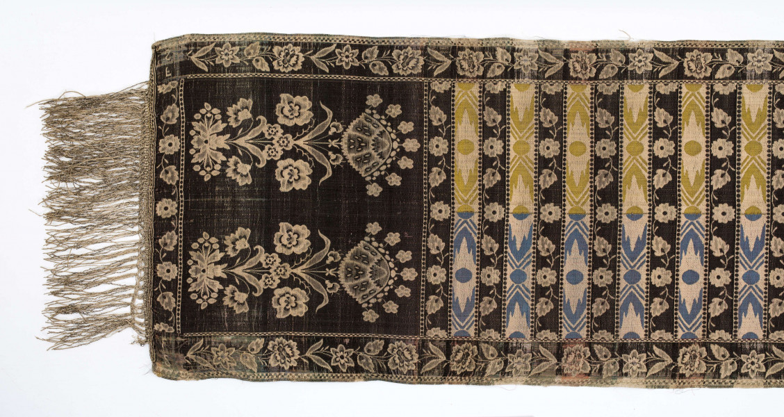 Pas kontuszowy czterostronny
Ornament: 
głowy - dwa motywy krzaczków kwiatowych wyrastających z liściastej rozety
środek - poprzeczne pólka na przemian z motywami wici kwiatowej i wydłużonych rombów z szelążkami
obrzeżenia - pionowe z motywami gałązek z kawiatami i liśćmi; poziome - motywy wici kwiatowej jak w pólkach
obwódki - w szachownicę, romby i groszki
Koloryt:
pr. - tło słomkowe, ornament różowy, biały, zielony, błękitny, jaznobrązowy
l. - tło czarne, jedynie w pólkach z rombamiw połowie błękitne, w połowie oliwkowozłote, ornament słomkowy
W narożnikach głów wytkana sygnatura: F/S (leżące)
Frędzla doszyta jedwabna, pleciona z nici kremowych z dodatkiem czarnych
