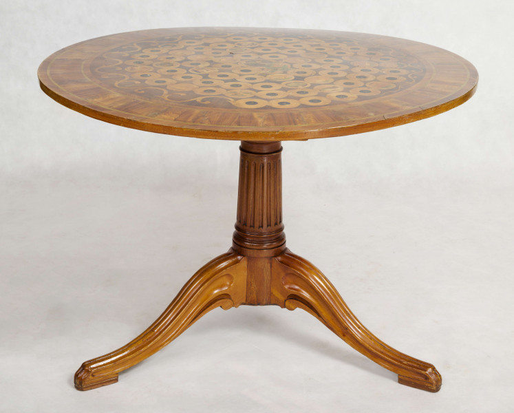 Blat stołu okrągły, uchylny, wsparty na profilowanym trzonie przechodzącym w  trzy esowate podporyz litego mahoniu . Na płycie  wielobarwna inkrustacja  z różych gatunków drewna częściowo barwionego i macicy perłowej: 76 pól okrągłych ułożonych spiralnie, w nich rozmaite przedstawienia (gęś, kostka do gry, filiżanka ze spodkiem, architektura, fragmenty parku, fontanna). W centrum płyty siedząca postać kobieca, półnaga, spowita zieloną tkaniną, trzymającą w prawej ręce uskrzydloną kulę (?), stanowiącą końcowy punkt gry.