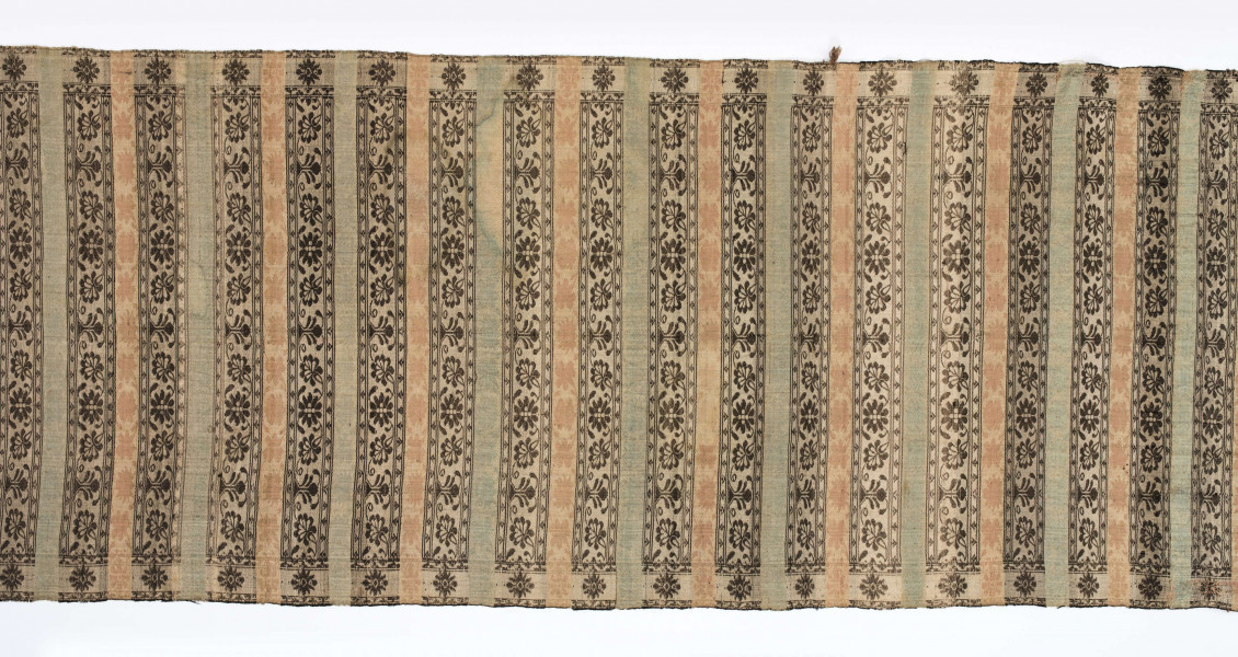 Pas kontuszowy dwustronny.
Ornament: 
głowy-trzy motywy stylizowanego kwiatu  goździka (każdy o czterech zgeometryzowanych płatkach)
wciąż pasa- poprzeczne pólka o kolejnych powtarzajacych się sekwencjach motywów:
-ciąg palmetek
-stylizowane kwiaty na tle łososiowym
-stylizowane kwiaty na tle zielonm
obrzeżenie- nieznacznie wyodrebnione dekorowane rozetką
Frędzla wysnuta z osnowy