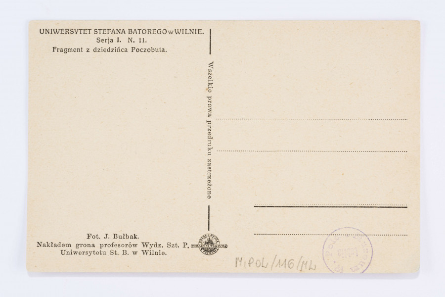 Pocztówka wykonana w sepii, przedstawia fragmnet Dziedzińca Poczobuta Uniwersytetu Stefana Batorego w Wilnie. Na pierwszym planie bezlistne drzewa, w tle ściana budynku z trzema oknami. Nad oknami słabo widoczne sztukaterie.
