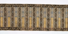 Pas 4-stronny. 
Ornament: głowy - krzaczki kwiatowe w wazonach; środek - poprzeczne pólka w układzie a,b,a,c (a - motyw wijacego sie wężyka, b - medaliony z rozetami, c - wić kwiatowa), obrzeża pionowe z gałązkami kwiatowymi, poziome - jak pólka c.
Koloryt: prawa strona - tło słomkowe, nieznacznie zróżnicowane w każdej połowie, zielen, błękit, żółty; lewa strona - tło brązowe głów i obrzeżeń, ornament - tło słomkowe, wzór j.w..
Fredzla doszyta jedwabna, pleciona, słomkowożółta