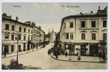 Pocztówka dwubarwna z widokiem na ul. Kapucyńską w Lublinie i fragment fasady Hotelu Wiktoria od strony ul. Krakowskiego Przedmieścia z widocznym w tle kościołem pobrygidkowskim (powizytkowskim)
AWERS: Z prawej strony kadru narożny budynek dwupiętrowy u zbiegu ulic Krakowskiego Przedmieścia i Kapucyńskiej, mieszczący Hotel Wiktoria. Na parterze gmachu widoczne szyldy przedsiębiorstw usługowych. Na fasadzie napis z nazwą hotelu w języku rosyjskim i fragment zadaszenia nad wejściem. Na chodniku przed hotelem słup na ogłoszenia. Z lewej strony ciąg kamienic. Wzdłuż ulic aleje niedużych drzewek liściastych. W głębi, zamykająca perspektywę ulicy Kapucyńskiej, gotycka czworoboczna wieża kościoła p. w. Wniebowzięcia Najświętszej Marii Panny Zwycięskiej. Pocztówka w tonacji sepii podkoloryzowana na niebiesko. Wzdłuż górnej krawędzi nadruk z napisem informacyjnym. 
REWERS:
Linatura w kolorze czarnym. Wyznaczone miejsce na korespondencje, adres i znaczek pocztowy. Pośrodku karty w pionie nadruk z informacją o wydawcy. W p. d. rogu numer serii. Brak śladów obiegu pocztowego.
