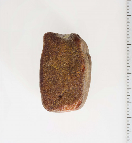 Półwytwór bursztynu kształtem zbliżony do sześcianu. Wyraźnie widoczne ślady szlifów i nawierceń.