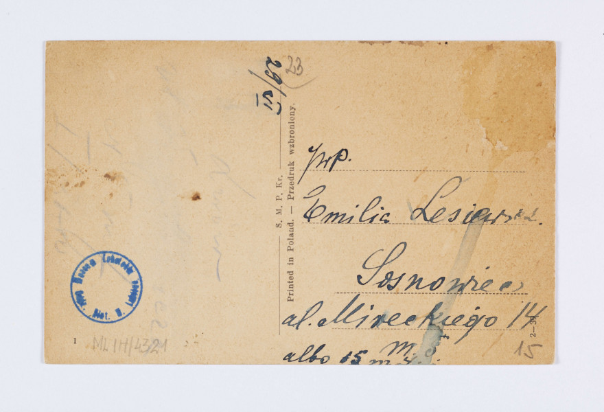 ML/H/4321 - Pocztówka czarnobiała z widokiem na Bramę Krakowską i Magistrat widoczne od ulicy Krakowskie Przedmieście w Lublinie
AWERS: Ujęcie w poziomie. Po lewej stronie, zza drzew, widoczny fragment budynku Magistratu. Do wejścia prowadzi czterokolumnowy portyk, nad którym znajduje się balkon. Perspektywę ulicy zamyka Brama Krakowska z przylegającymi dwupiętrowymi kamienicami i skrzydłem Hotelu Centralnego. Po prawej stronie od budynku zaparkowany samochód osobowy. Brama otynkowana, z obrazem Matki Boskiej na przedbramiu. Pod zegarem, na wyższej kondygnacji, widoczna galeria biegnąca wokół budowli. Na ulicy przechodnie. Pod fotografią wzdłuż dolnej krawędzi nadruk informacyjny czarną czcionką. 
REWERS: Czarna linatura. Wyznaczone pole na adres i korespondencje. Nadruk z informacją o nakładcy w kolorze czarnym umieszczony pionowo pośrodku karty. Pismem odręcznym (niebieskim atramentem) wpisany adres odbiorcy – Emilii Lesiewicz w Sosnowcu. W polu na korespondencję ślady po usuniętym tekście. Naniesiona jedynie data dzienna i miesięczna. Napisy w języku polskim. Brak śladów obiegu pocztowego.
