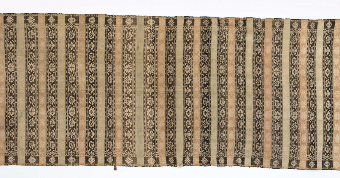 Pas kontuszowy dwustronny.
Ornament: 
głowy-trzy motywy stylizowanego kwiatu  goździka (każdy o czterech zgeometryzowanych płatkach)
wciąż pasa- poprzeczne pólka o kolejnych powtarzajacych się sekwencjach motywów:
-ciąg palmetek
-stylizowane kwiaty na tle łososiowym
-stylizowane kwiaty na tle zielonm
obrzeżenie- nieznacznie wyodrebnione dekorowane rozetką
Frędzla wysnuta z osnowy