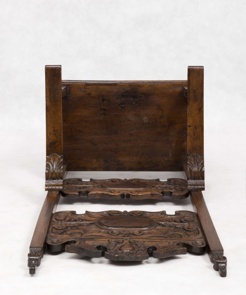 Fotel drewniany z  siedziskiem i oparciem drewnianym bez wyściełania, na prostych nogach z czterema łączynami. Nogi tylne przechodzą w ramiaki boczne oparcia. Oparcie prostokątne, lekko odchylone do tyłu. Zaplecek ażurowy złożony z dwóch bogato rzeźbionych desek:
- górna w ornamenty wolutowe wokół środkowago owalnego medalionu, z ozdobnie wyciątą dolną krawędzią i wyodrębnionym zwieńczeniem w kształcie przełamanego tympanonu z centralnym kartuszem
- dolna - węższa, powtarza główny motyw zdobienia.
Poręcze graniaste zakończone małymi wolutkami, u nasady rzeźbione liście akantu, podpórki w środkowej części rzeźbione. Płyta siedzenia prostokątna z rzeźbionym fartuchem z przodu. Łączyny boczne i tylna - graniaste, łączyna przednia w postaci deski o ozdobnym wykroju, rzeźbionej w ornamenty wolutowe.