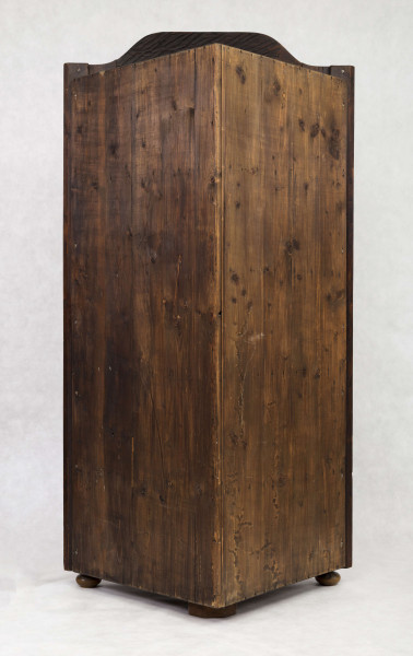 Szafa dwukondygnacyjna, z falistym zwieńczeniem, na nóżkach w kształcie spłaszczonych kul, wnętrze na planie trójkąta z półkami o falistych frontach. W części dolnej drzwi o wypukłym profilu zdobione fornirowanym wzorem: w centrum romb z przedstawieniem ptaka na gałęzi, wokół wzór szachownicy, krawędzie ujęte w ramę. W części górnej drzwi o falistym zwieńczeniu  oszklone szybkami łączonymi ołowiem.  
Oryginalny jest tylko front - pochodzący być może z szafy ściennej - całe wnętrze wykonano w XX wieku.  
