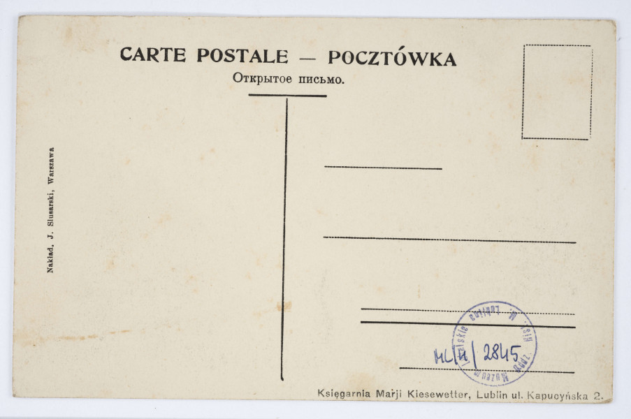 Pocztówka - Katedra i Wieża Trynitarska w Lublinie (ujęcie w poziomie).
AWERS: Widok frontu Katedry oraz skrzydła dawnych zabudowań kolegium jezuickiego z Wieżą Trynitarską. Ujęcie od strony placu katedralnego. Widoczni przechodnie. Po prawej stronie świątyni zejście na ulicę Królewską. U góry nadrukiem w kolorze czarnym napisy informacyjne.
REWERS: Czarna linatura. Wyznaczone pole na adres i korespondencje oraz znaczek pocztowy. Nadruki w kolorze czarnym z informacjami o nakładcy oraz wydawcy. Napisy w języku polskim, rosyjskim i francuskim. Brak korespondencji oraz śladów obiegu pocztowego.
