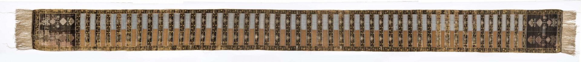 Pas kontuszowy czterostronny.
Ornament:
głowy- dwa motywy ukwiecinych łodyg umieszczonych w wazonach przypominajacych palmety- stylizowane , silna geometryzacja motywów. 
wciąż pasa- poprzeczne pólka z motywem wici kwiatowej i rzuty rozetek, na przemian
obrzeżenia- pionowe z motywem zgeometryzowanej wici kwiatowej poziome- jak w  pólkach 
kolor:pr. -  tło głów i pólek z wicią i obrzeżeń  żółte gładkie pólka w połowie różowe  w połowie różowe, wić brązowa kwiaty niebieskie, łososiowe i żółte
l. tło brązowe wzór słomkowy
Frendzla doszyta słomkowa.
