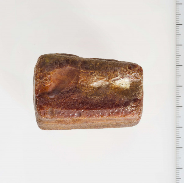 Półwytwór bursztynu kształtem zbliżony do sześcianu. Wyraźnie widoczne ślady szlifów i nawierceń.