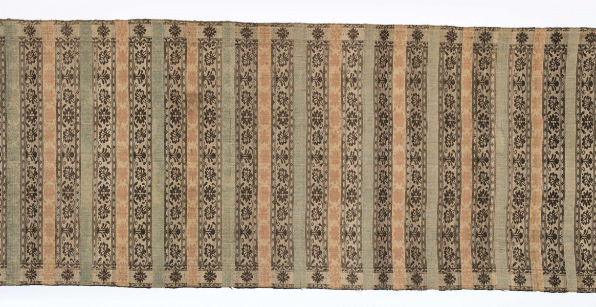 Pas kontuszowy dwustronny.
Ornament: 
głowy-trzy motywy stylizowanego kwiatu  goździka (każdy o czterech zgeometryzowanych płatkach)
wciąż pasa- poprzeczne pólka o kolejnych powtarzajacych się sekwencjach motywów:
-ciąg palmetek
-stylizowane kwiaty na tle łososiowym
-stylizowane kwiaty na tle zielonm
obrzeżenie- nieznacznie wyodrebnione dekorowane rozetką
Frędzla wysnuta z osnowy