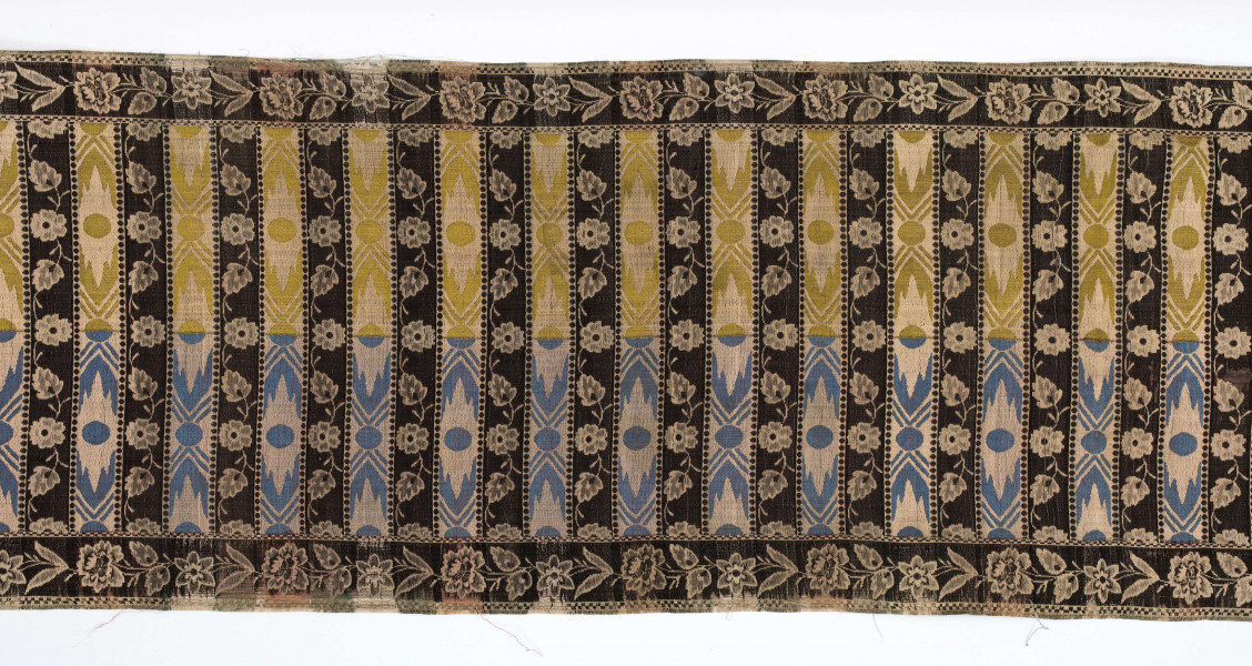 Pas kontuszowy czterostronny
Ornament: 
głowy - dwa motywy krzaczków kwiatowych wyrastających z liściastej rozety
środek - poprzeczne pólka na przemian z motywami wici kwiatowej i wydłużonych rombów z szelążkami
obrzeżenia - pionowe z motywami gałązek z kawiatami i liśćmi; poziome - motywy wici kwiatowej jak w pólkach
obwódki - w szachownicę, romby i groszki
Koloryt:
pr. - tło słomkowe, ornament różowy, biały, zielony, błękitny, jaznobrązowy
l. - tło czarne, jedynie w pólkach z rombamiw połowie błękitne, w połowie oliwkowozłote, ornament słomkowy
W narożnikach głów wytkana sygnatura: F/S (leżące)
Frędzla doszyta jedwabna, pleciona z nici kremowych z dodatkiem czarnych
