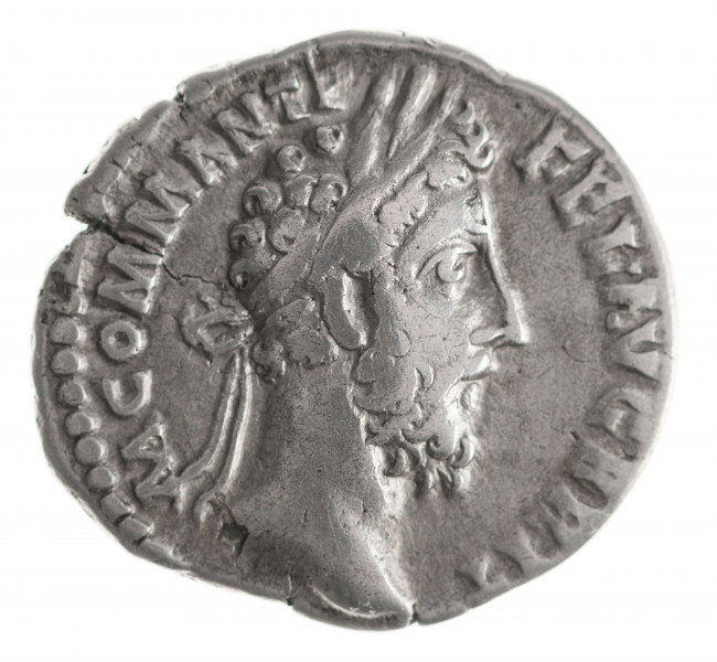 N/11383/ML - Av.: Popiersie cesarza z wieńcem laurowym w prawo. W otoku: M COMM ANT P FEL AVG BRIT
Rv.: Wiktoria stojąca w lewo z prawą stopą wspartą na hełmie. Przed nią palma zwieńczona tarczą z napisem: VO . DE ( czyli VOTA DECENNALIA). W otoku: [SAE]C FEL P M TR [P XI IMP V]II COS V P P
