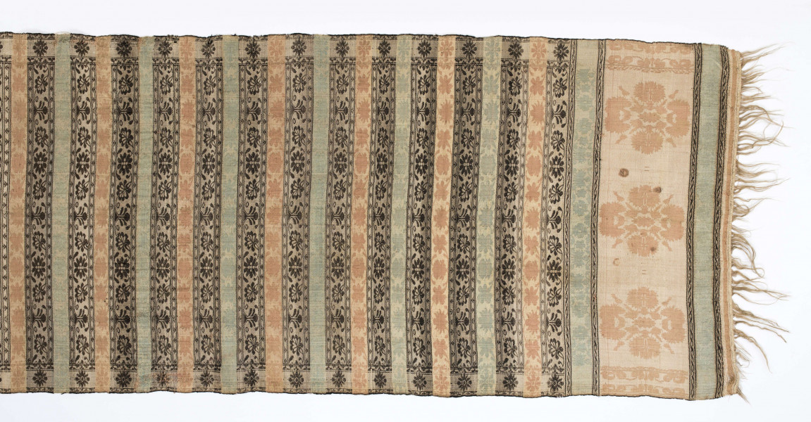 Pas kontuszowy dwustronny.
Ornament: 
głowy-trzy motywy stylizowanego kwiatu  goździka (każdy o czterech zgeometryzowanych płatkach)
wciąż pasa- poprzeczne pólka o kolejnych powtarzajacych się sekwencjach motywów:
-ciąg palmetek
-stylizowane kwiaty na tle łososiowym
-stylizowane kwiaty na tle zielonm
obrzeżenie- nieznacznie wyodrebnione dekorowane rozetką
Frędzla wysnuta z osnowy