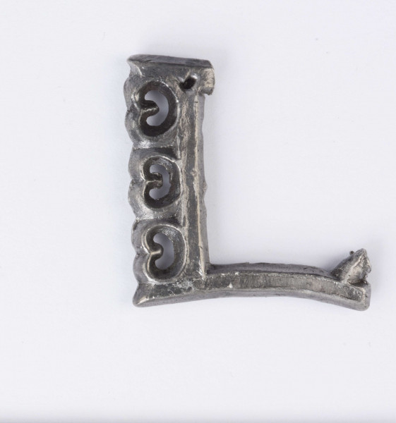 Sprzączka do pasa zachowana fragmentarycznie wykonana ze srebra, zdobiona . Ramka prostokątna. Przednia część ramki zdobiona trzema wypukłymi sercowatymi ornamentami z wyciętymi środkami w kształcie półksiężyca. Wszystkie wypukłości wyżej opisanego ornamentu oraz krawędzie sprzączki zdobione drobnym granulatem. Surowiec - srebro. Wymiary: średnia grubość 0,4; wymiary boków ramki 3,4 i 3,2 cm. Stan zachowania dobry. 